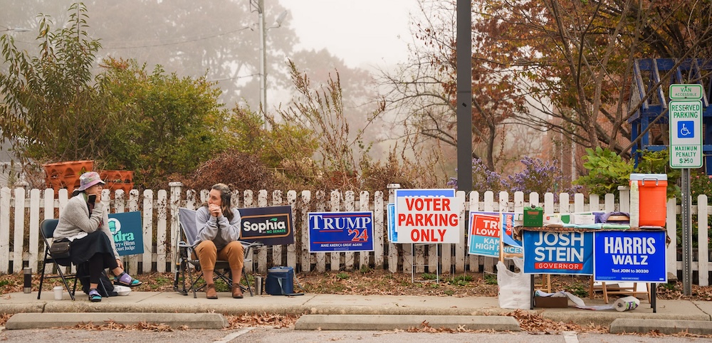 Campaign volunteers sitting in chairs outside the polling place at E.K. Poe Elementary School.