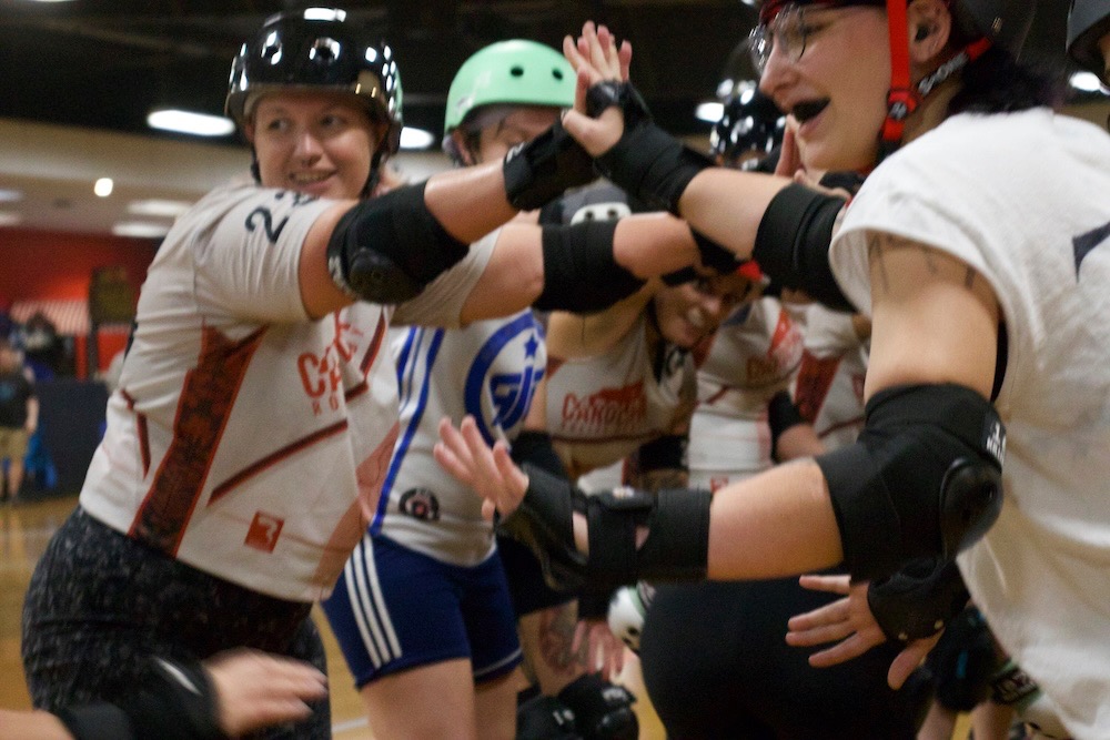 Roller derby players exchange high fives after a bout at Wheels.