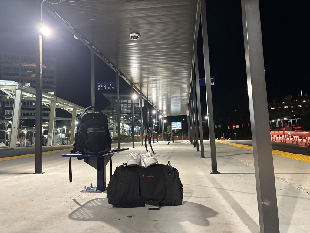 A black duffle bag, a backpack, and a pair of white sneakers