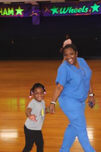 A woman and child hold hands while roller skating.