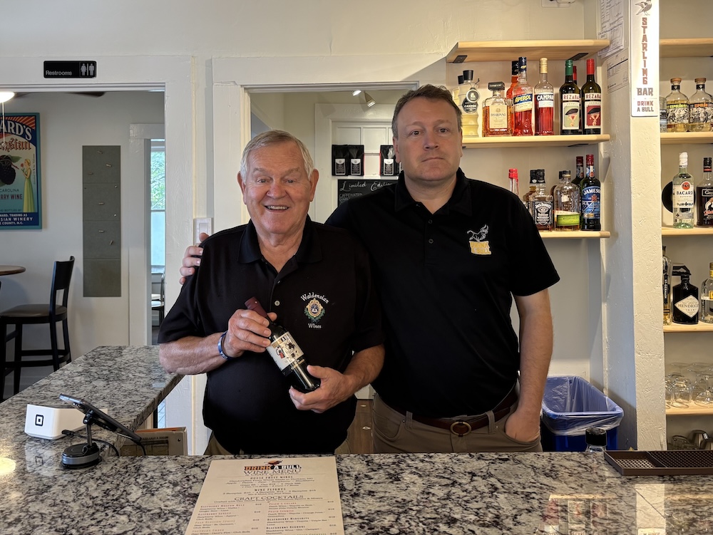 two men in black polos behind a bar