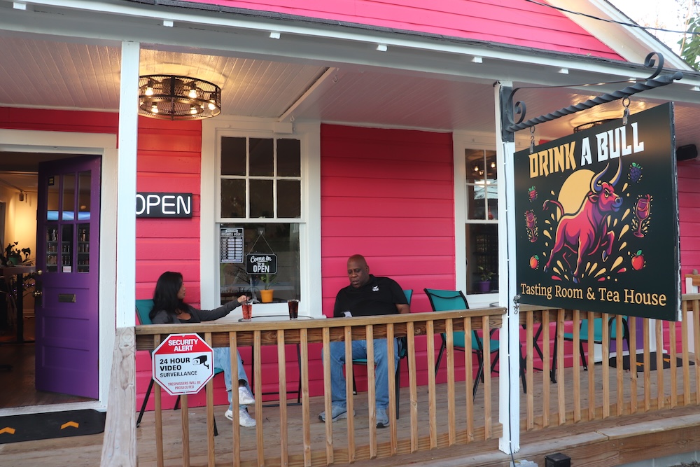 Pink wine shop with people drinking on porch