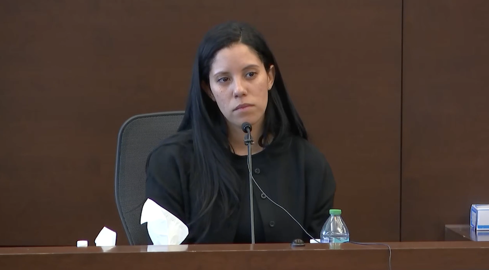 Karena Rosario, wearing a black blazer and black top, testifies in court.